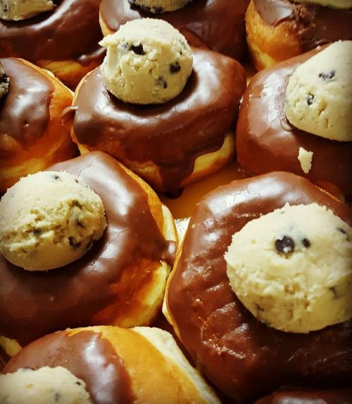 Close-up of chocolate-glazed donuts topped with cookie dough balls.