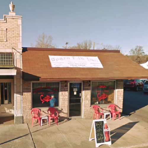 Exterior of Spare Rib Inn, featuring a sign, red chairs outside, and a chalkboard menu on the sidewalk.