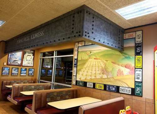 Interior of a restaurant featuring a mural of rolling hills and a display of vintage license plates on the wall.