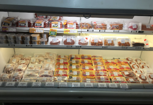A refrigerated display case filled with various packaged meats and prepared food items, labeled for easy identification.