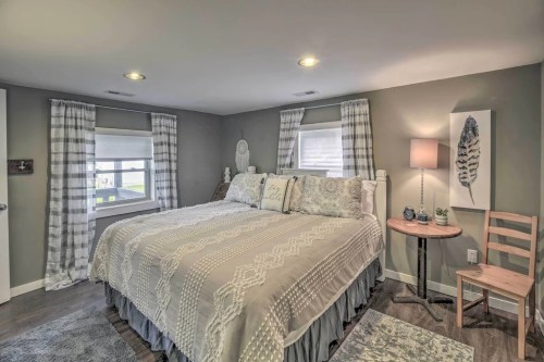 Cozy bedroom with a large bed, decorative pillows, a lamp, and a chair, featuring soft lighting and neutral colors.