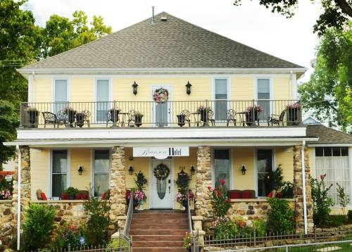 A charming yellow house with a stone base, featuring a balcony with chairs and flower decorations.