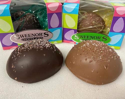Two chocolate confections, one dark and one milk, topped with sprinkles, displayed in colorful packaging.