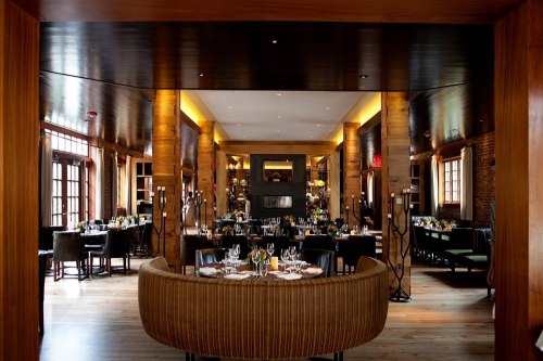 Elegant restaurant interior featuring wooden accents, stylish seating, and tables set for dining. Warm, inviting atmosphere.