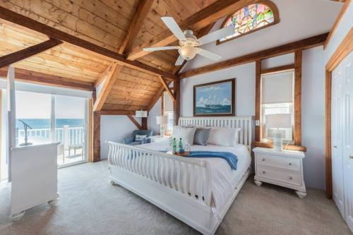 Bright, airy bedroom with a wooden ceiling, large bed, and ocean view through sliding doors. Cozy and inviting atmosphere.