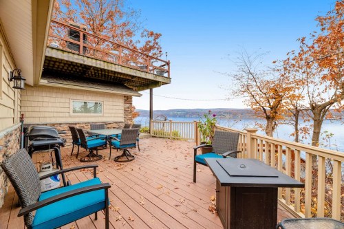 A scenic deck with seating and a fire pit, overlooking a lake surrounded by autumn foliage.