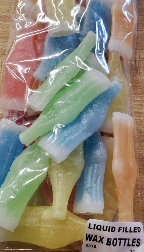 A bag of colorful wax bottles filled with liquid, featuring blue, green, yellow, and red hues.