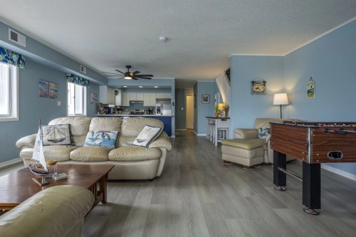 Cozy living room with beige leather furniture, a foosball table, and a view of a kitchen in a light blue setting.