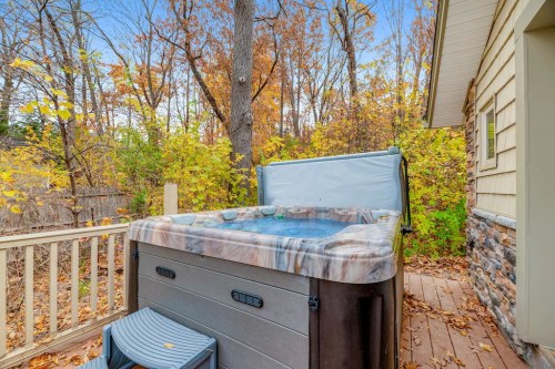A hot tub on a wooden deck surrounded by colorful autumn trees and a house.