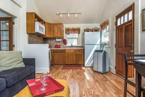 Cozy kitchen and living area with wooden cabinets, a dining table, and natural light from windows.