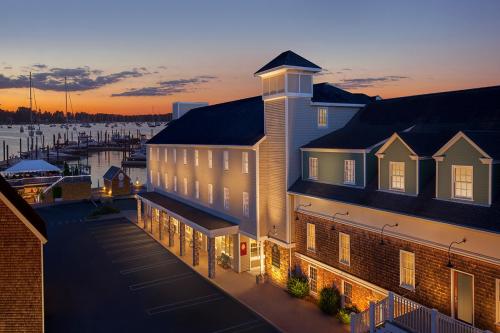 A waterfront hotel at sunset, with boats in the marina and a colorful sky reflecting on the water.
