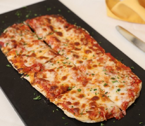 A rectangular pizza topped with melted cheese and tomato sauce, garnished with parsley, on a black serving board.