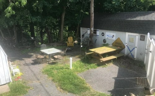 A backyard scene with a picnic table, chairs, and various decorations against a backdrop of trees and a shed.