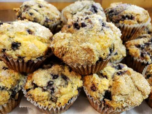 A close-up of freshly baked blueberry muffins topped with sparkling sugar, arranged in a pile.