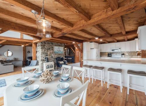 Bright, open kitchen and dining area with wooden beams, a round table set for four, and a cozy living space in the background.