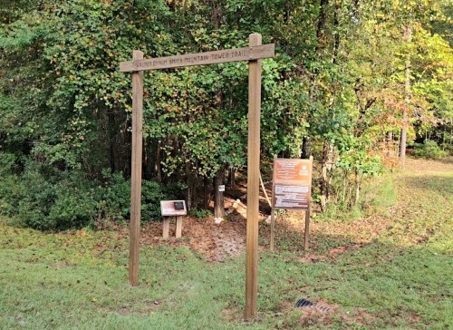Wooden sign marking the entrance to the "Walnut County Smith Mountain Trail," surrounded by trees and greenery.