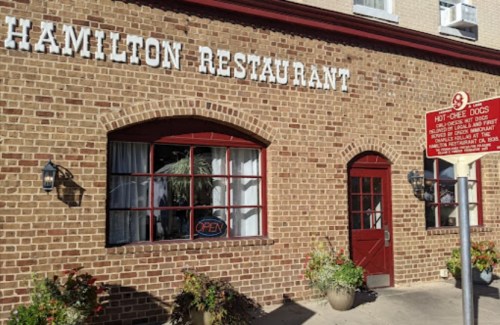 Exterior of Hamilton Restaurant featuring a brick facade, open sign, and a nearby informational sign.