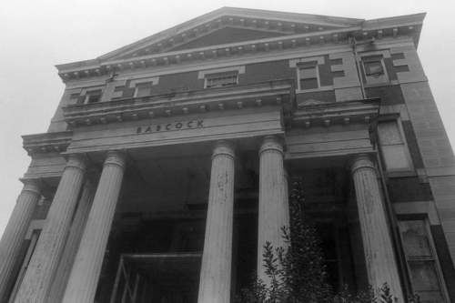 Black and white image of a grand, abandoned building with tall columns and the name "Fabcock" above the entrance.