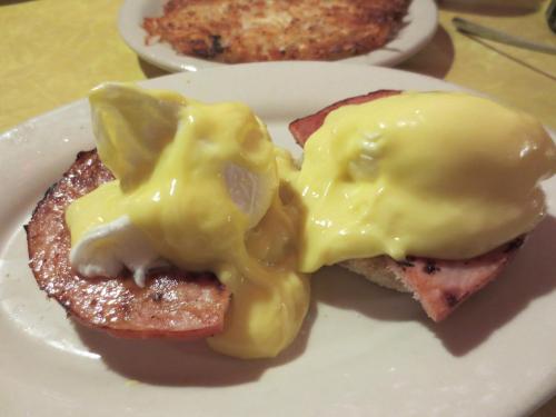 Two poached eggs topped with hollandaise sauce on slices of ham, served on a plate.