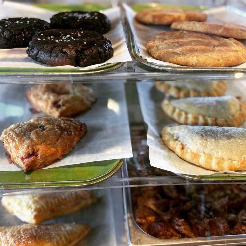 A display case filled with various baked goods, including cookies, pastries, and scones.