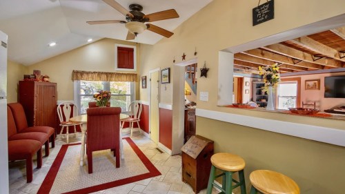 Cozy kitchen and dining area with a table, chairs, and warm decor, featuring a ceiling fan and natural light.