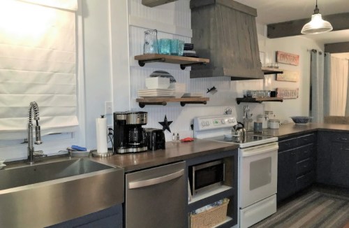 Modern kitchen with stainless steel appliances, wooden shelves, and a cozy atmosphere.