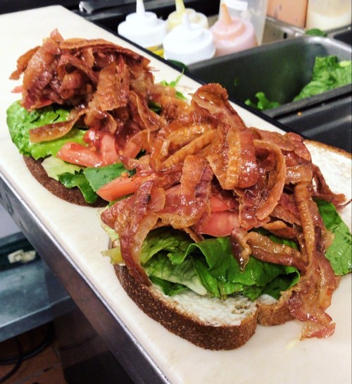 A sandwich with layers of crispy bacon, lettuce, and tomato on whole grain bread, ready to be served.