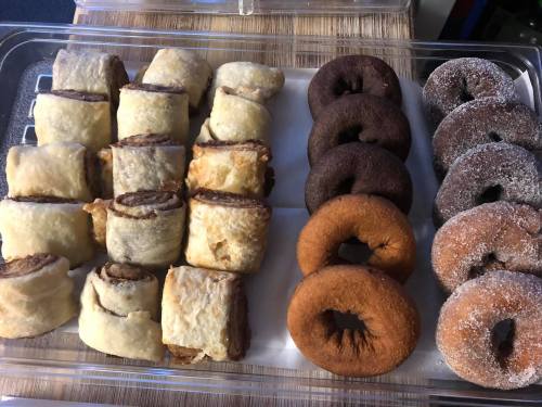 A tray of pastries featuring cinnamon rolls and assorted donuts in various colors and textures.