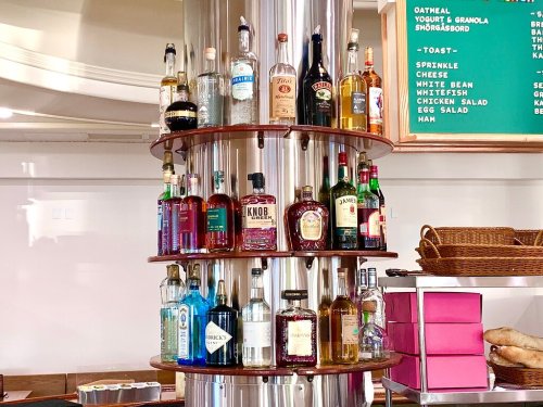 A circular display of various liquor bottles on wooden shelves in a bar setting.