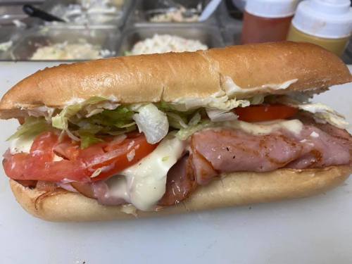 A delicious sandwich with ham, lettuce, tomato, and mayonnaise on a toasted bun.