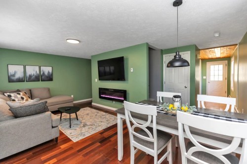 Cozy living area with green walls, a sofa, dining table, and a mounted TV above an electric fireplace.