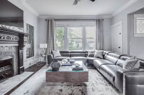 Modern living room featuring a large leather sectional, glass coffee table, and elegant decor with natural light.