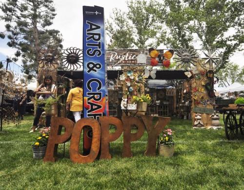 A vibrant outdoor arts and crafts fair with colorful displays and a large "POPPY" sign in the foreground.