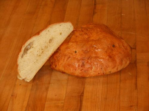 A round loaf of bread with a slice cut out, resting on a wooden surface.