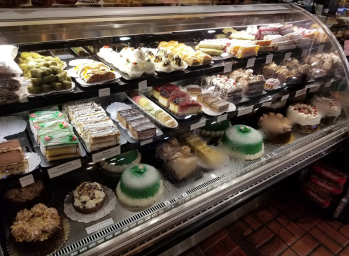 A display case filled with various colorful pastries, cakes, and desserts, showcasing a tempting assortment.