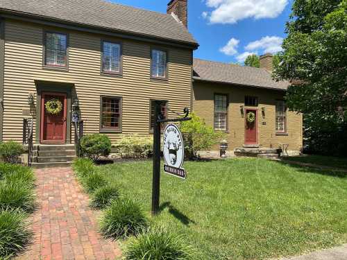 Two charming houses with red doors and wreaths, surrounded by green grass and trees, with a sign reading "Mason's Way."