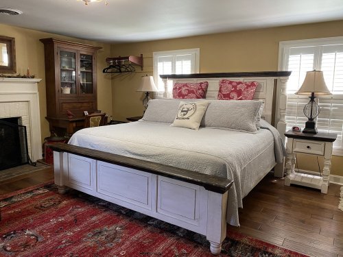 Cozy bedroom featuring a large bed with decorative pillows, a wooden dresser, and warm lighting.