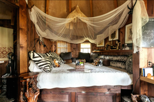 Cozy wooden bedroom with a canopy bed, zebra-patterned decor, and warm, rustic accents.