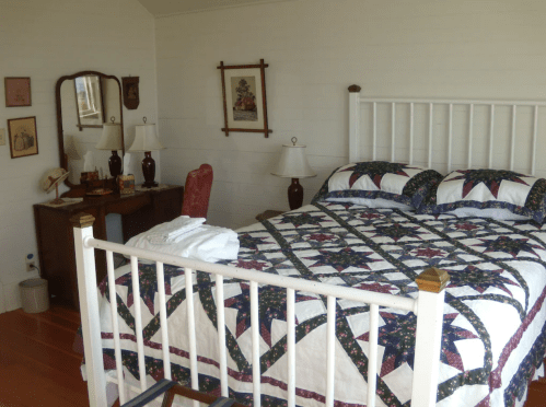 Cozy bedroom featuring a quilted bed, wooden furniture, and soft lighting from bedside lamps.