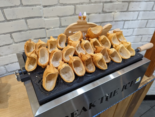 A display of empty waffle cones arranged on a metal stand, ready to be filled with ice cream.