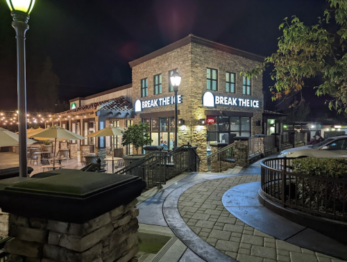 A well-lit restaurant named "Break the Ice" at night, featuring outdoor seating and a welcoming atmosphere.