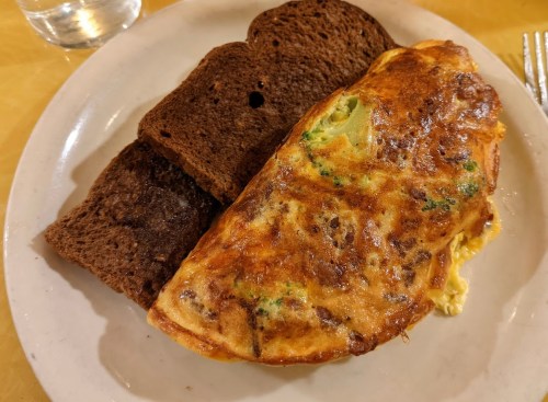 A plate with a fluffy omelette and two slices of dark brown bread.