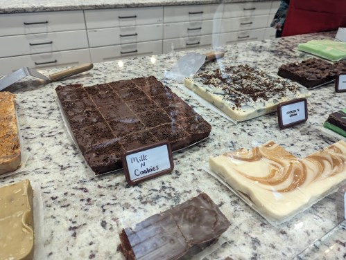 A display of various fudge flavors, including milk n' cookies, on a marble countertop in a candy shop.