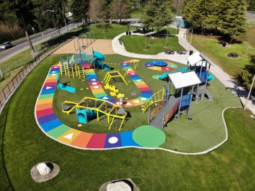 Aerial view of a colorful playground with various play structures and a vibrant, patterned ground.