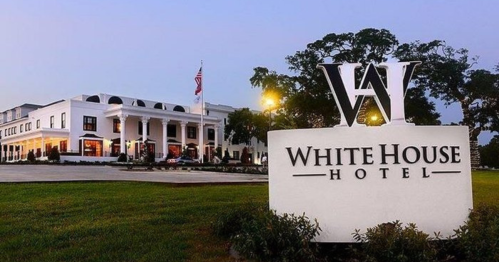 Exterior view of the White House Hotel, featuring a large sign and elegant architecture at dusk.
