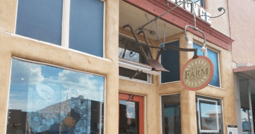 Exterior of "The Farm" restaurant, featuring a sign and decorative elements like a plow above the entrance.