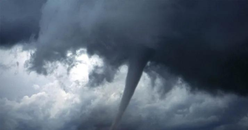 A tornado descends from dark storm clouds, creating a dramatic funnel shape against a cloudy sky.