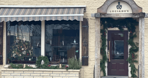 A festive restaurant exterior decorated with garlands and a Christmas tree in the window.