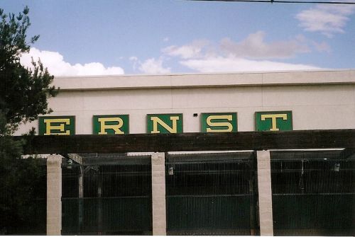Sign on a building displaying the name "ERNST" in green and yellow letters against a blue sky.