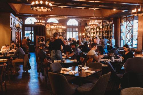 A bustling restaurant interior with patrons dining, chatting, and staff serving in a warm, inviting atmosphere.